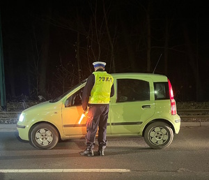 Na zdjęciu umudurowany policjant badający trzeźwość kierowcy