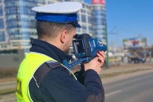 Na zdjęciu widoczny umundurowany policjant z ręcznym miernikiem prędkości