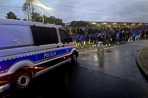 Na zdjęciu policyjny radiowóz oraz kibice