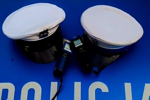Na zdjęciu policyjne czapki i alkomaty na masce radiowozu