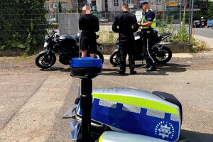 N a zdjęciu część policyjnego motocykla oraz policjanci podczas legitymowania