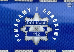 Na zdjęciu policyjna gwiazda na radiowozie z napisem pomagamy i chronimy