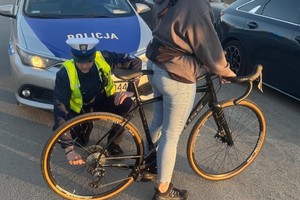 Na zdjęciu policyjny radiowóz i policjant przy rowerze