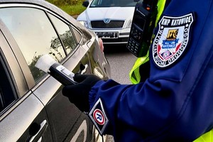 Na zdjęciu policjant podczas badania trzeźwości trzymający w ręku alkomat