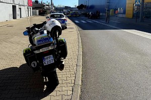 Na zdjęciu policyjny motocykl, radiowozy na miejscu wypadku drogowego