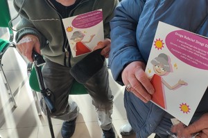Na zdjęciu seniorzy z materiałami profilaktycznymi