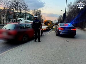 Na zdjęciu samochód podczas kontroli, policjant i nieoznakowany radiowóz