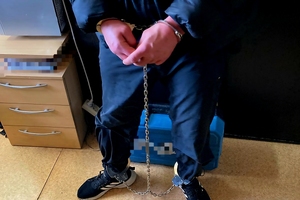mężczyzna z założonymi kajdankami na dłonie i nogi